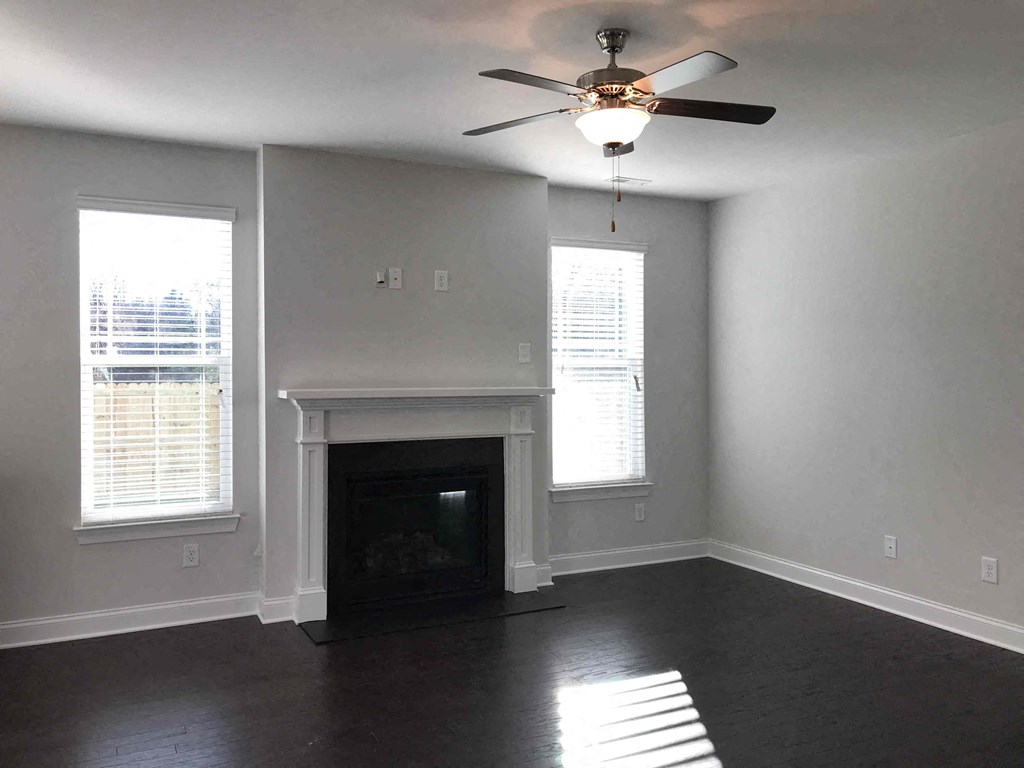 A living room with a fireplace and a ceiling fan.