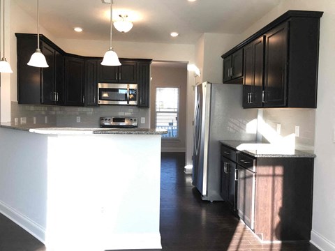 A kitchen with black cabinets and a white island.