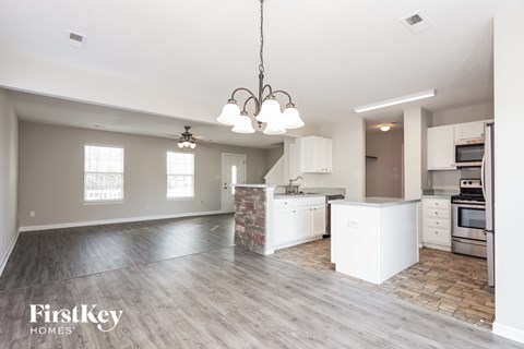 an open kitchen and living room with white cabinets and a wood floor