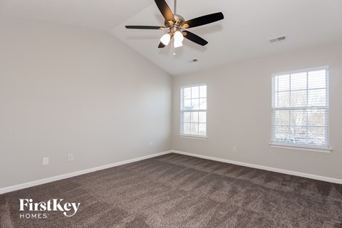 a living room with carpet and a ceiling fan