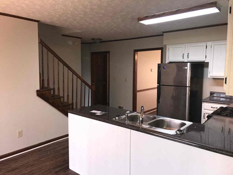 a kitchen with a sink and a refrigerator and a staircase