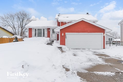 A red house with a white garage door in the snow.