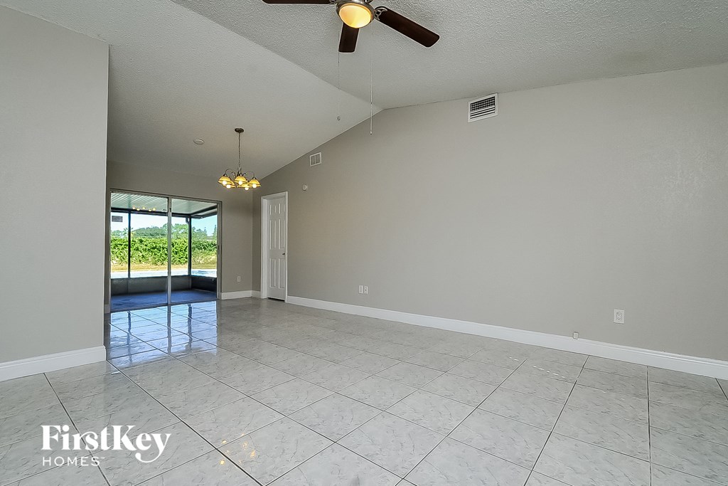 a clean empty living room with a ceiling fan and a window