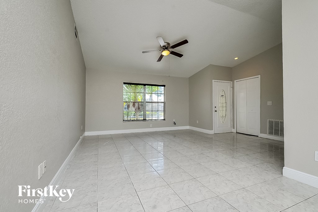a spacious living room with tile flooring and a ceiling fan