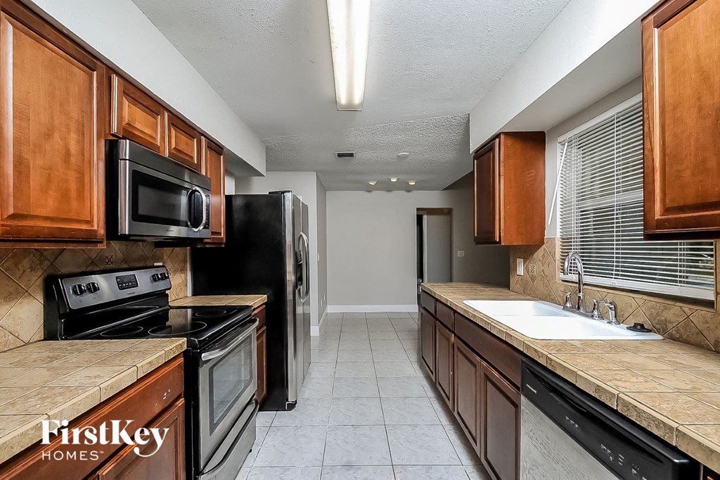 a kitchen with wood cabinets and black appliances and a sink