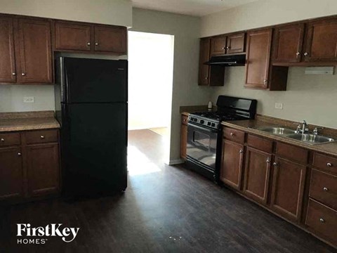 an empty kitchen with dark wood cabinets and a black refrigerator