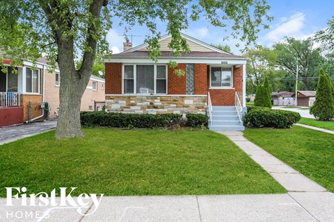 the front of a brick house with stairs and a lawn