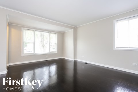 a clean and empty room with black resin flooring and two windows