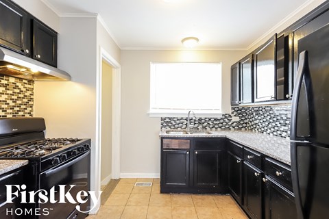 a kitchen with black cabinets and a stove and a window