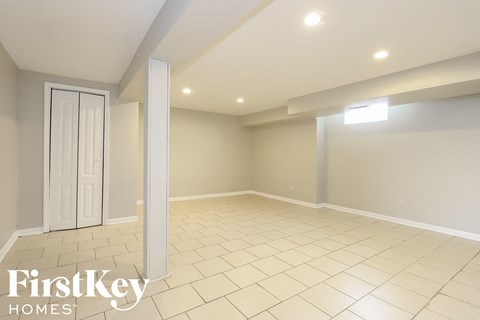 the spacious living room has a large tiled floor and a white door
