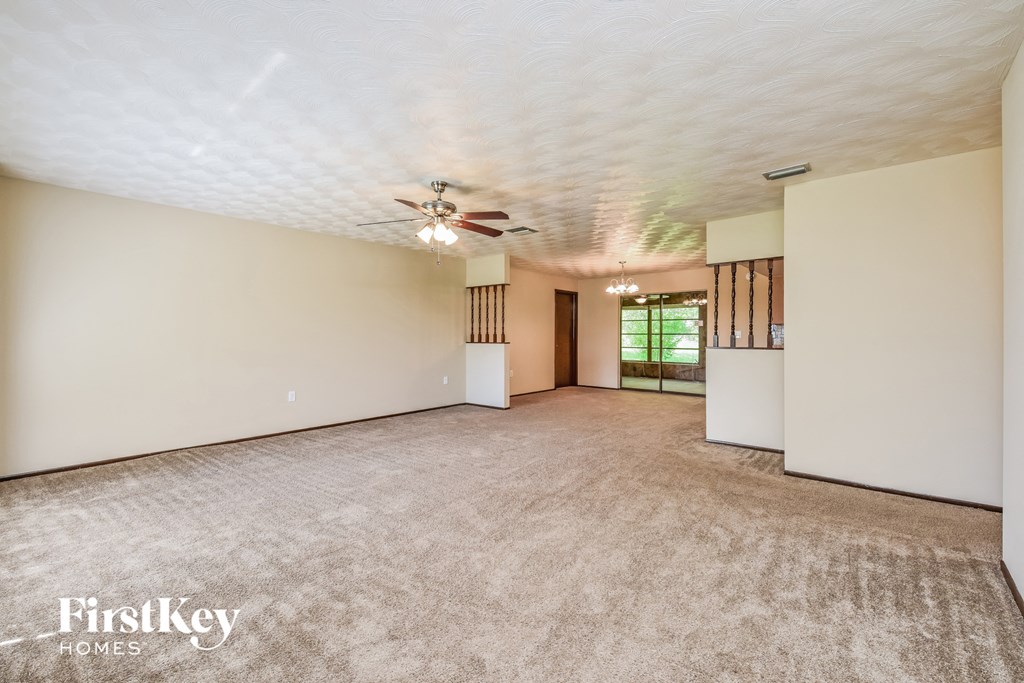 an empty living room with a ceiling fan and white walls
