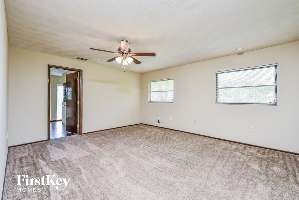 the living room is spacious and clean with a ceiling fan
