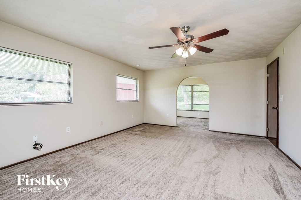 an empty living room with a ceiling fan and a large window