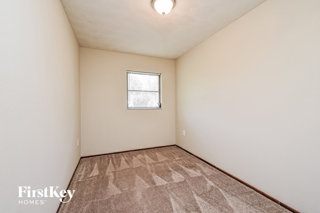 a bedroom with white walls and carpet and a window