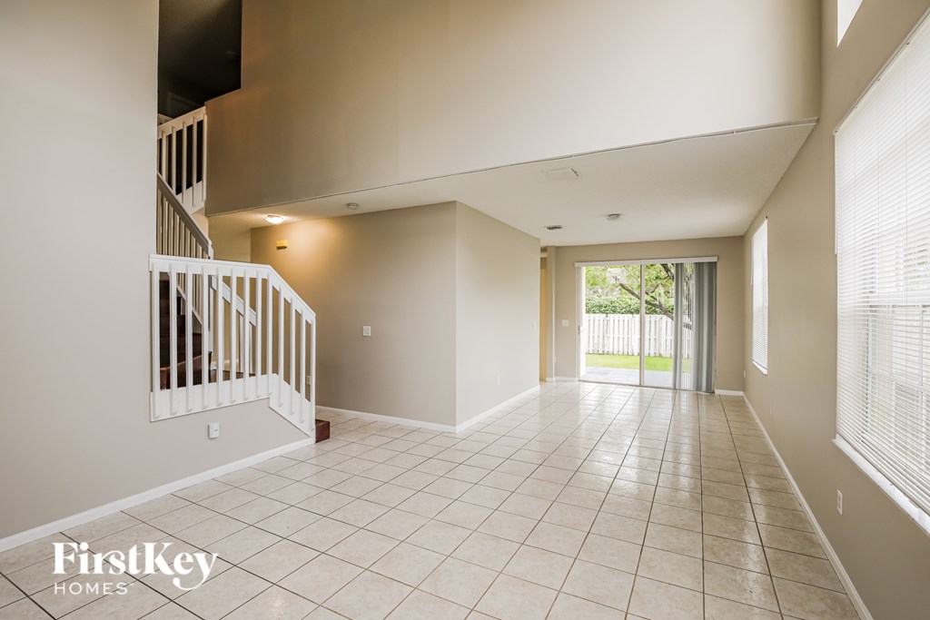 A spacious room with a staircase on the left and a sliding glass door on the right.