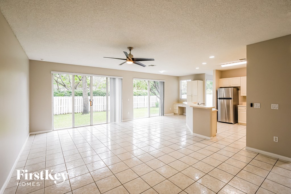 A spacious room with a fan and sliding glass doors leading to a backyard.