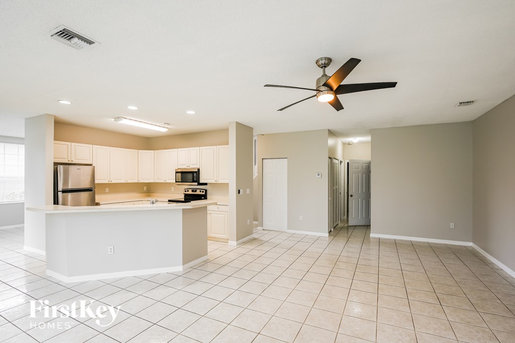 A spacious kitchen and living room with a ceiling fan.
