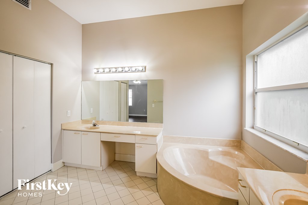 A bathroom with a tub, sink, and mirror.
