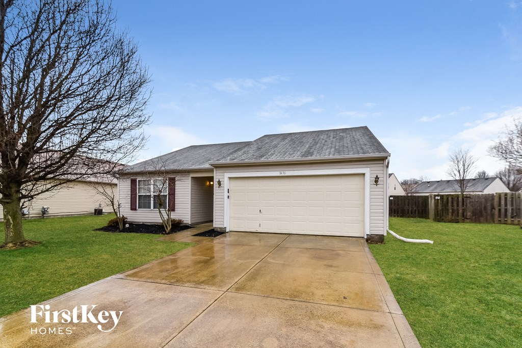 A house with a garage and a tree in front of it.