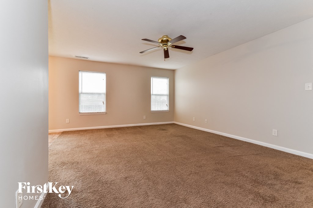 A room with a carpeted floor and a ceiling fan.
