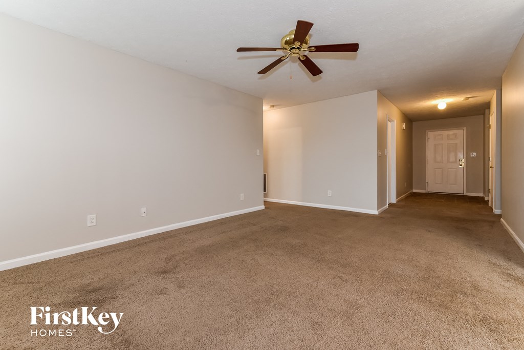 A carpeted room with a ceiling fan and a FirstKey Homes logo.