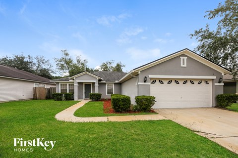 A house with a garage door and a driveway in front of it.