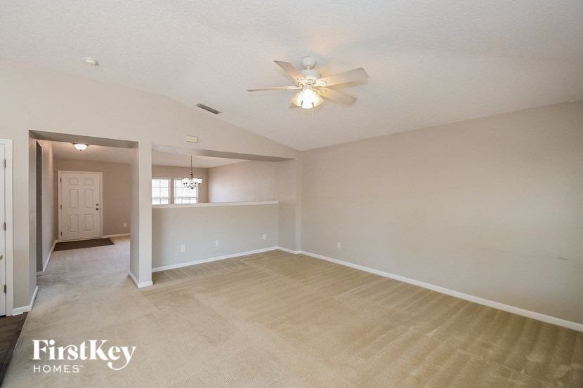 an empty living room and kitchen with a ceiling fan