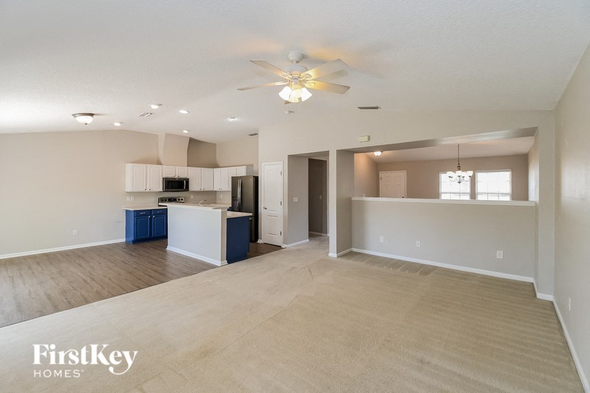 an empty living room and kitchen with a ceiling fan