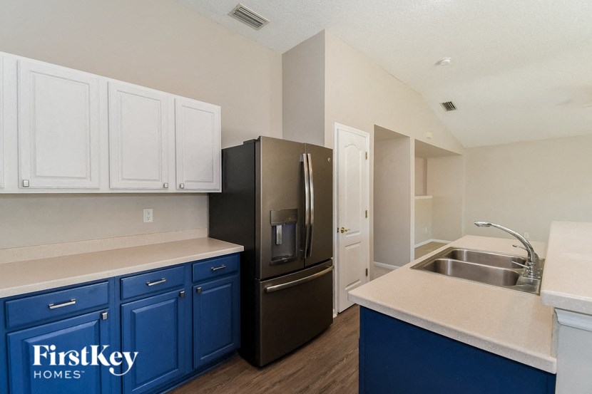 a kitchen with blue and white cabinets and a black refrigerator