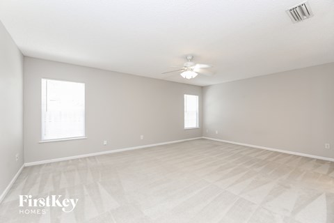 A spacious empty room with a FirstKey Homes logo.