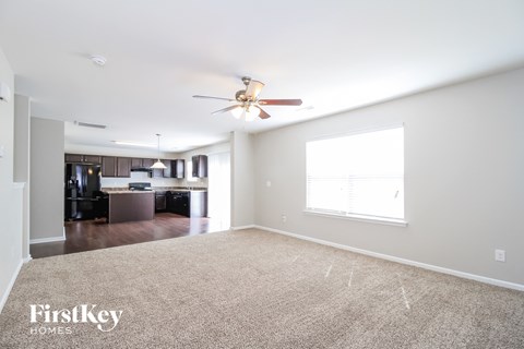 A spacious room with a carpeted floor and a ceiling fan.