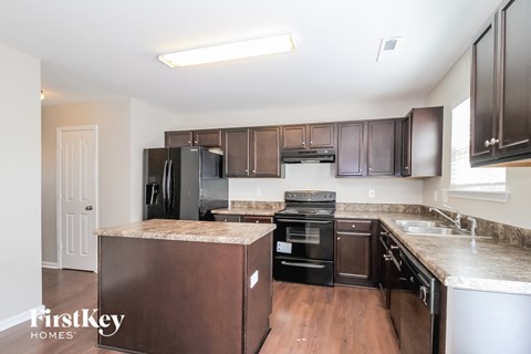 A kitchen with a brown island and black appliances.
