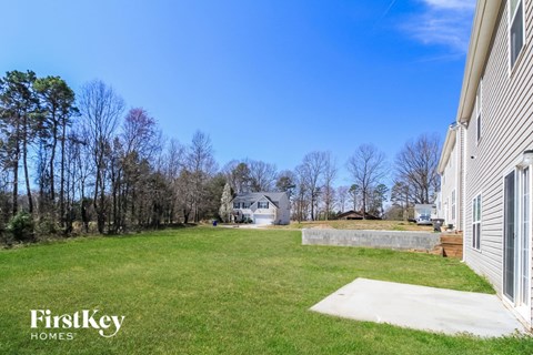 A house with a yard and trees in the background.