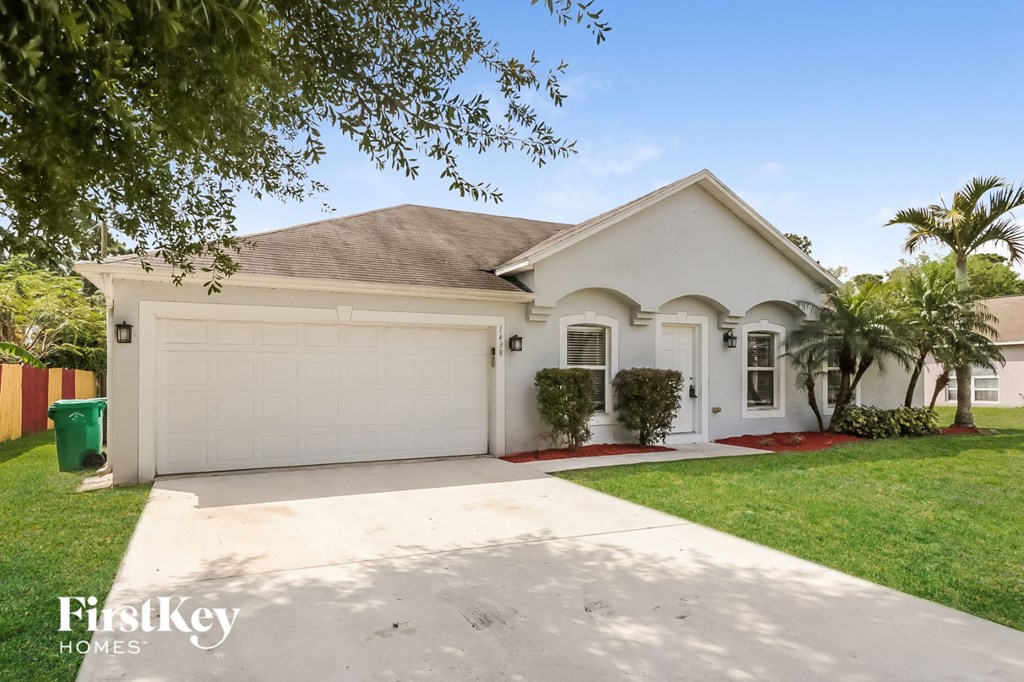 a white house with a white garage door and a lawn
