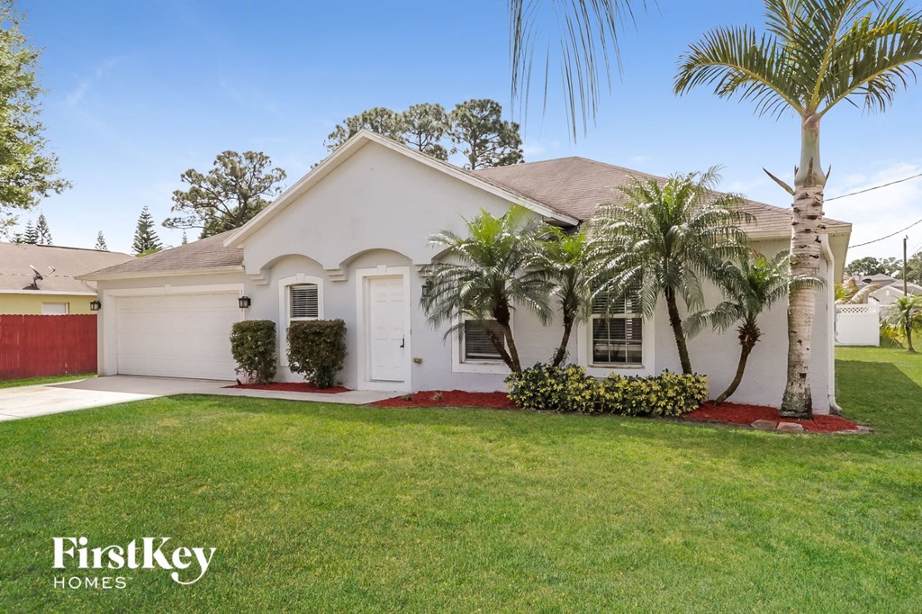 a white house with palm trees and a lawn