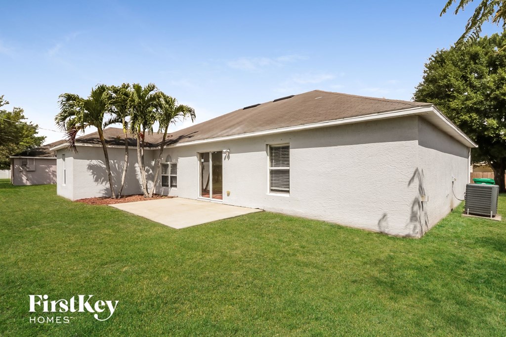 a white house with a yard and palm trees