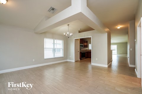 A spacious living room with a chandelier and hardwood floors.