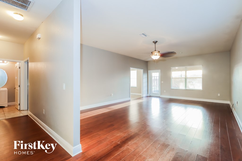 A spacious room with wooden floors and a ceiling fan.