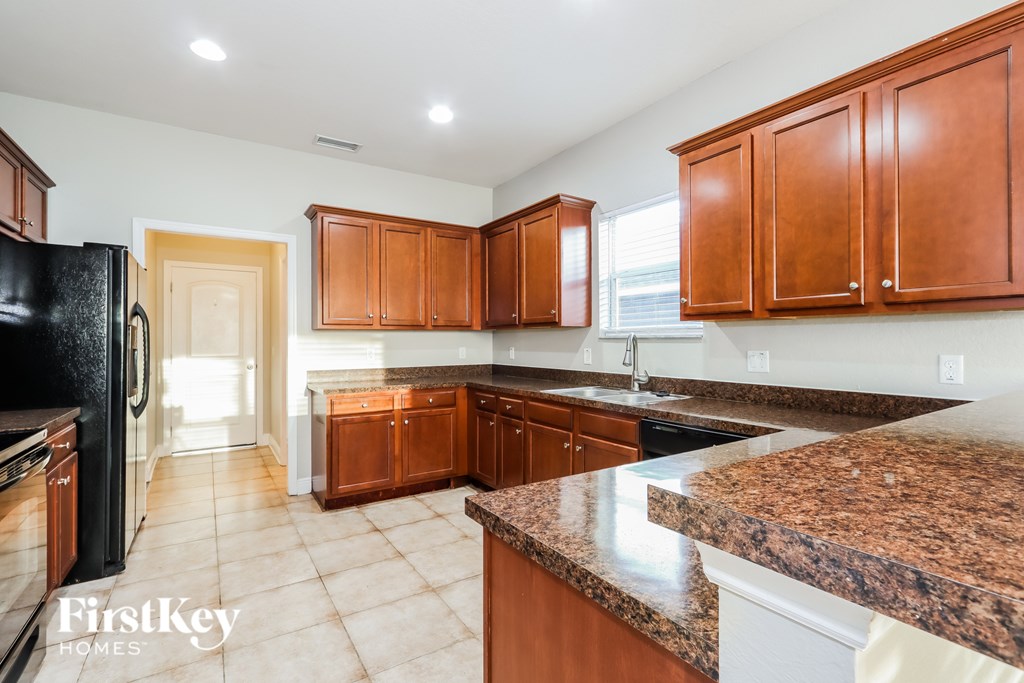 A kitchen with brown cabinets and a granite counter top.