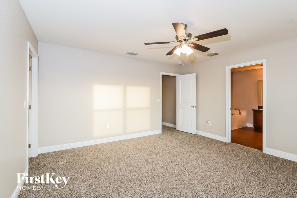 A spacious room with a ceiling fan and carpeted floor.