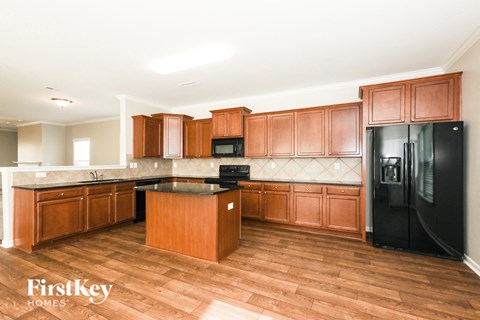 A kitchen with wooden cabinets and a black fridge.