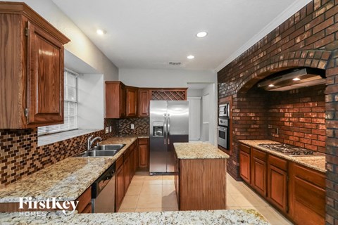 A kitchen with wooden cabinets and a brick wall.