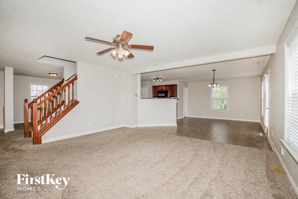 A spacious room with a ceiling fan and a staircase.