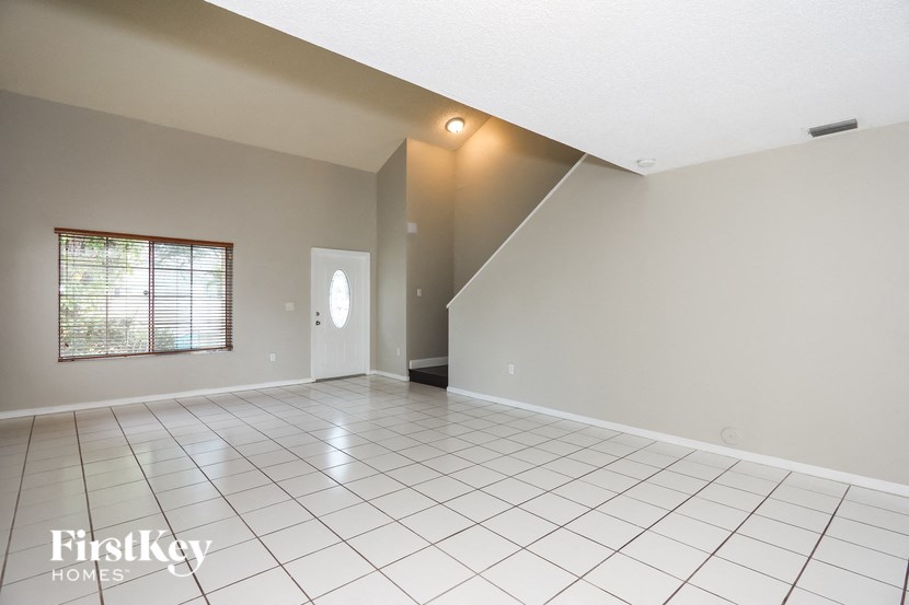 an empty living room with a white tiled floor