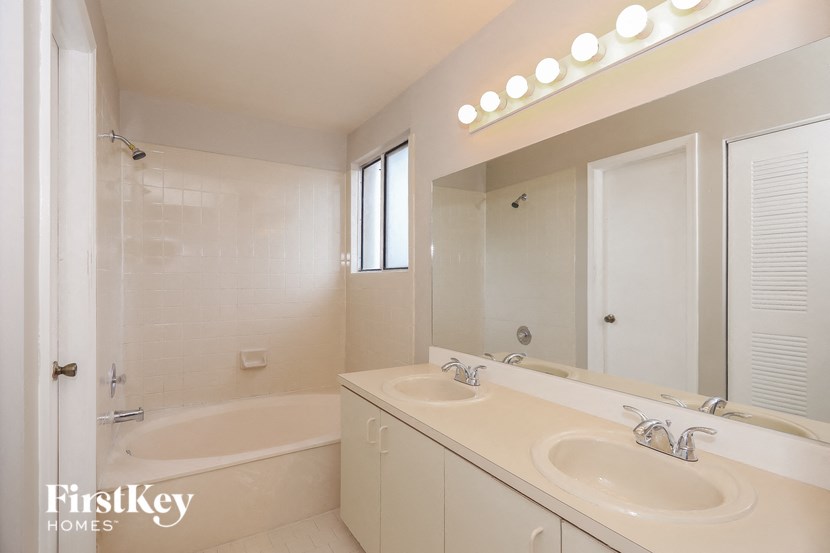 a bathroom with two sinks and a tub and a mirror