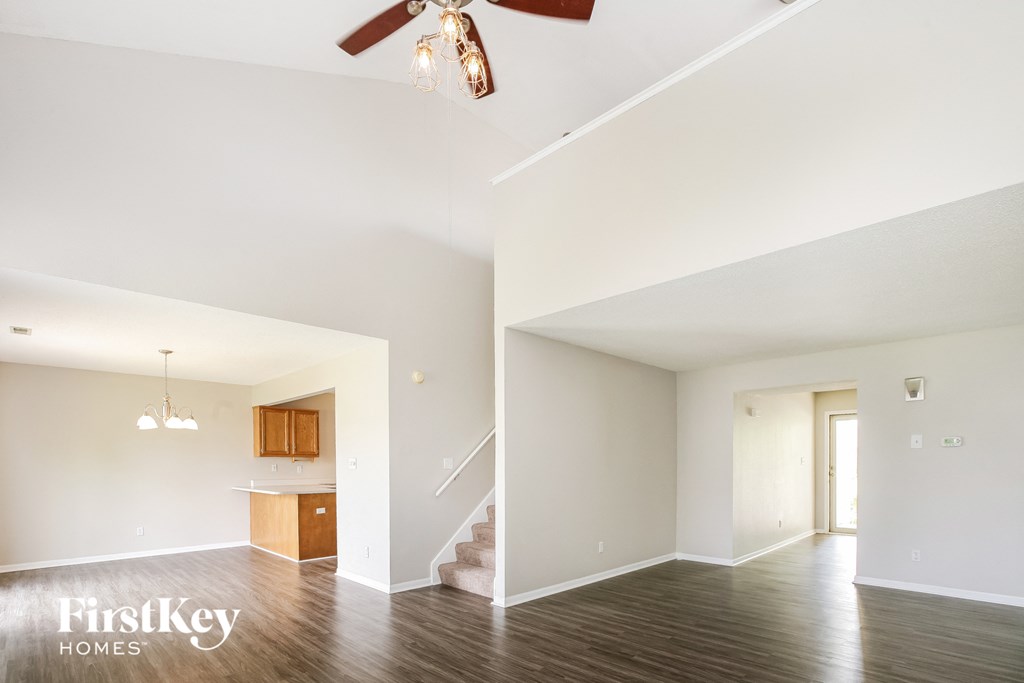 an empty living room and kitchen with a ceiling fan