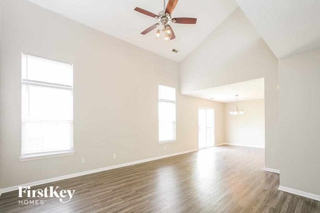 the spacious living room with ceiling fan and wood flooring