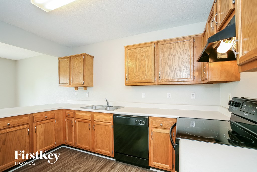 a kitchen with wooden cabinets and a black stove and dishwasher