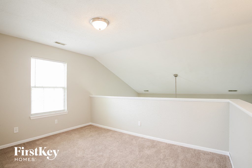 a bedroom with white walls and carpet and a window