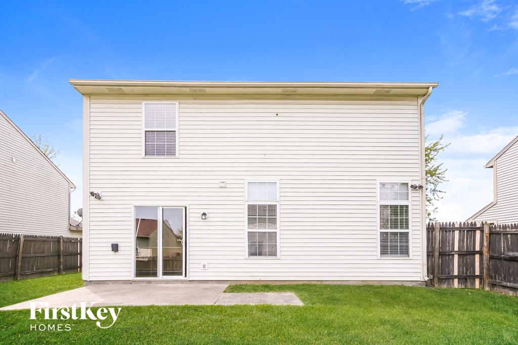 the outside of a white house with a lawn and a wooden fence